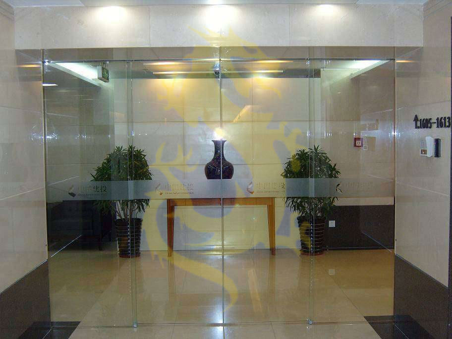 Cửa kính văn phòng với bình hoa trang trí trên bàn gỗ và hai chậu cây xanh hai bên